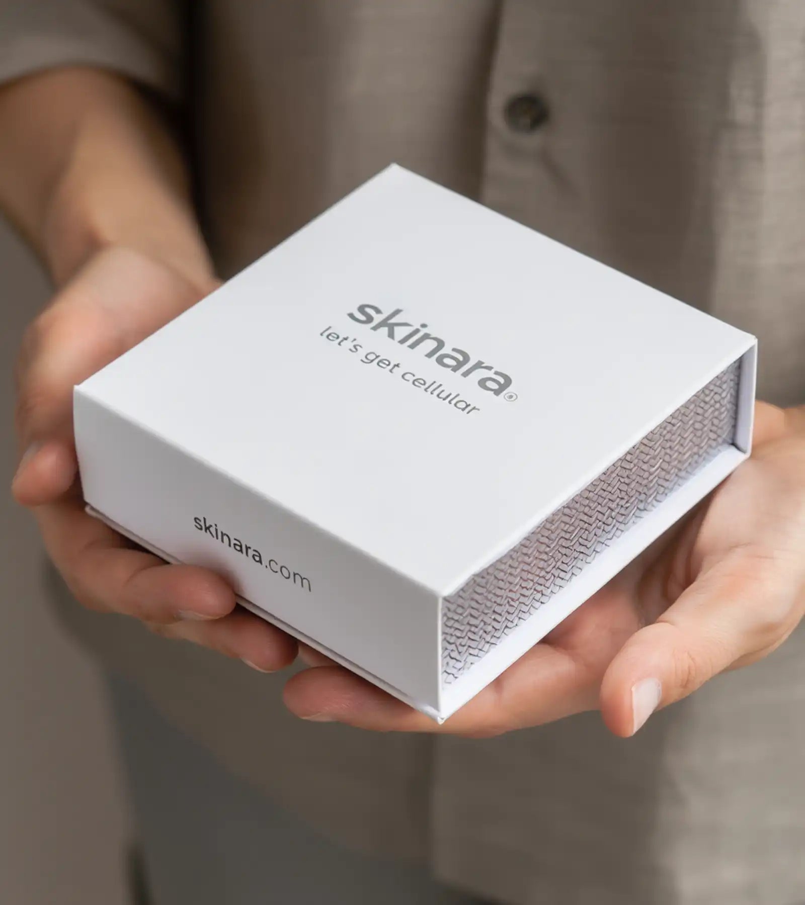 Man holding a white skinara hair growth serum hair treatment box in his hands