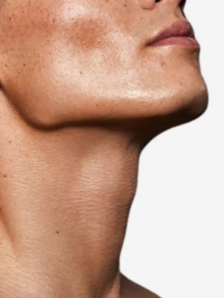 Close-up of a persons neck and jawline with a neutral background