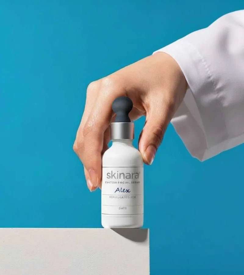 hand holding a skinara custom serum bottle against a blue background