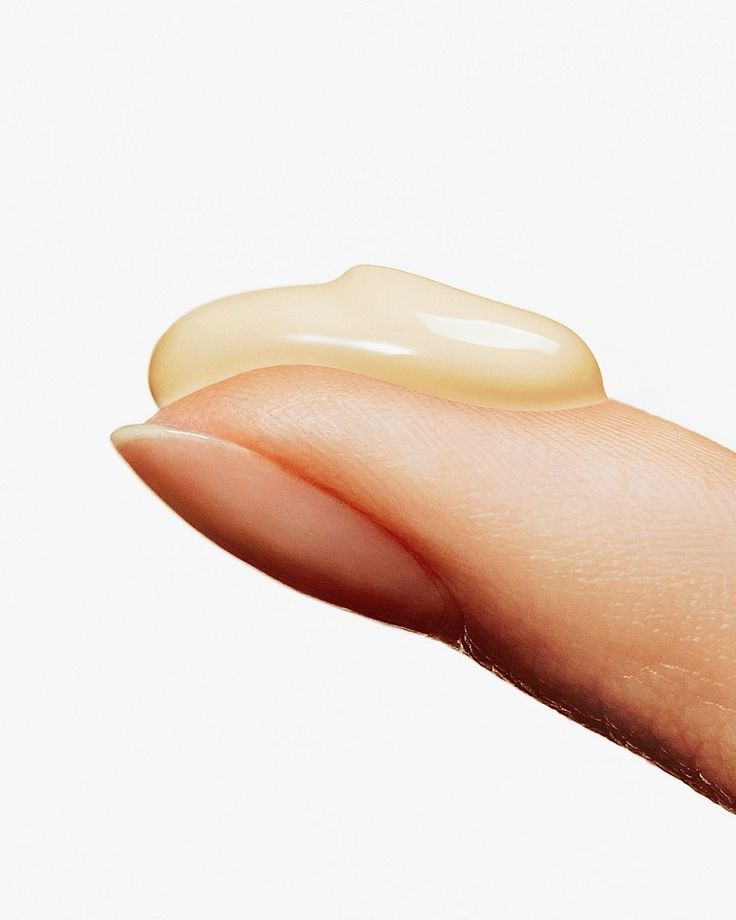 Hand with small amount of antioxidant serum on index finger against white background