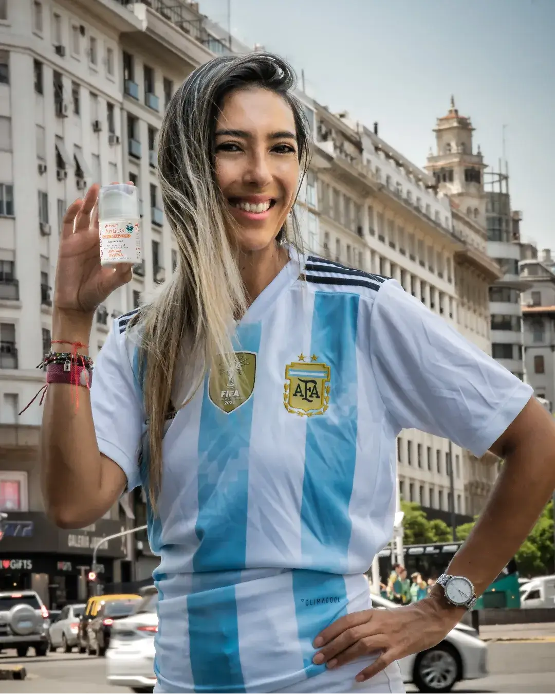 skinara brand ambassador in Argentina soccer jersey holding Agescreen sunscreen in Buenos Aires