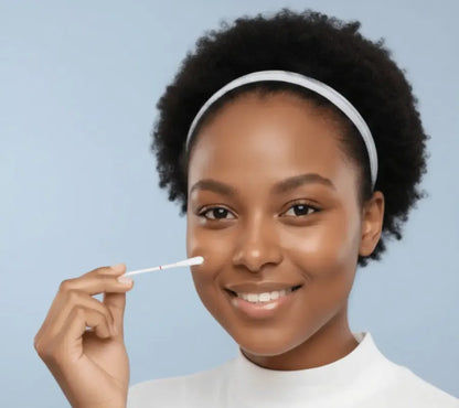 Woman using a swab to collect a sample from her cheek against a light blue background