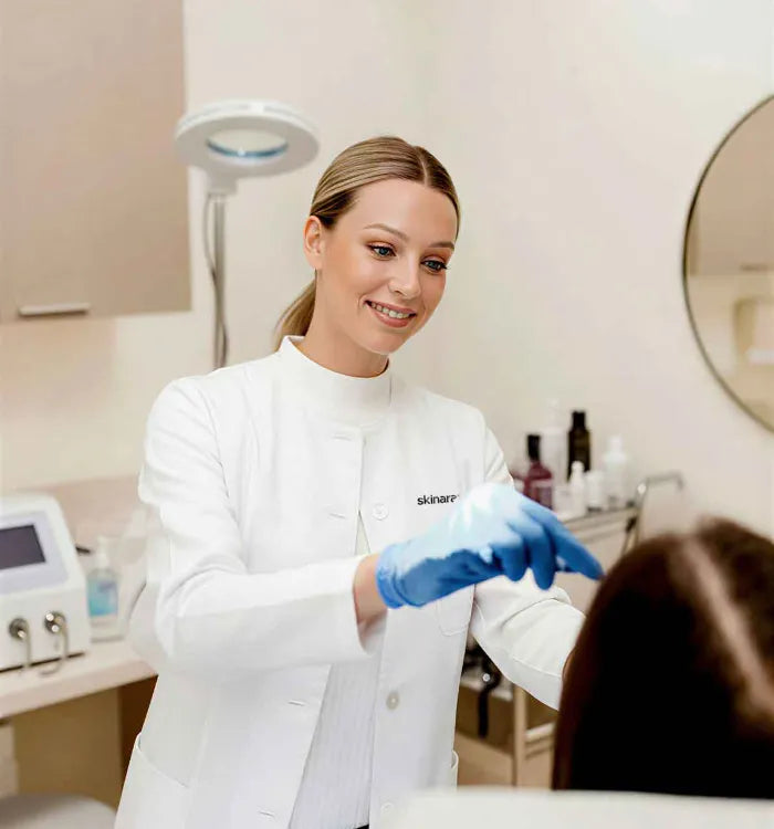 female dermatologist in a clinic setting wearing a white lab coat examining a patient