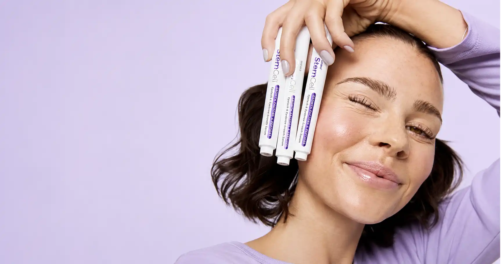 A woman holding three Skinara StemCell eyelash and eyebrow growth serums