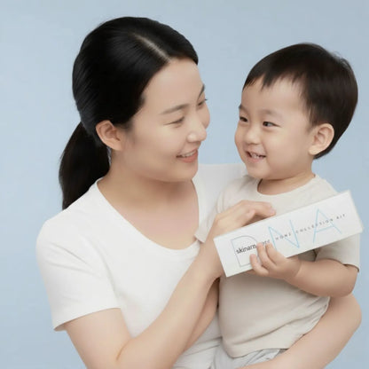 Woman holding a child who is holding a skinara skin DNA testing kit product box against a light blue background