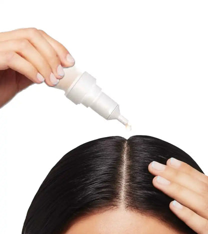 woman applying skinara hair growth serum to her hairline with a dropper