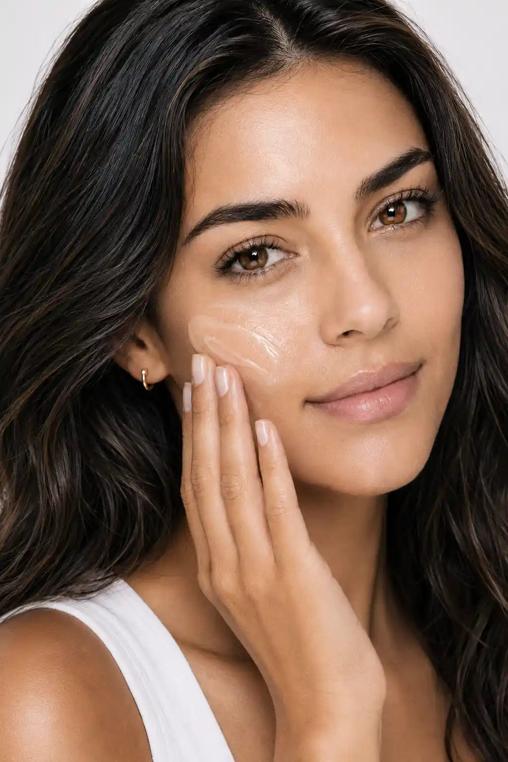 Woman applying AgeScreen Clear sunscreen to her cheek